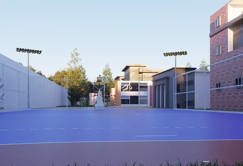 Floodlit sports court between campus buildings at dusk